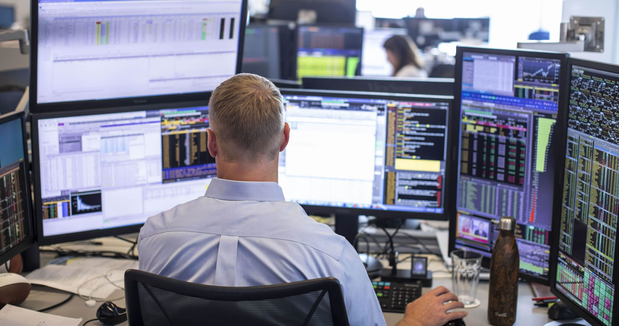 The back of a man in front of several computer screens